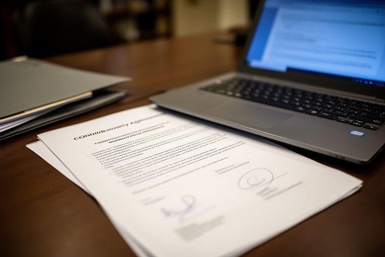 Confidentiality agreement beside a briefing folder and laptop in a quiet legal office